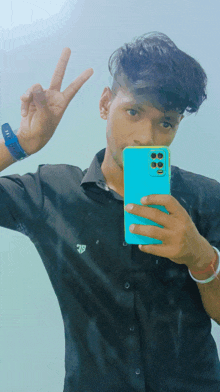 a young man in a black shirt is taking a selfie with a blue phone