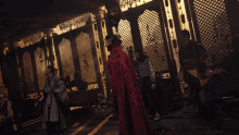 a man in a red cape stands in a room