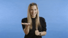 a woman in a black shirt is giving a thumbs up .