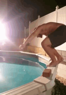 a man jumps into a swimming pool at night