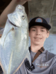 a man holding a fish wearing a shirt that says hanadaya on it