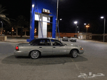 a silver car is parked in front of a blue building with arabic writing