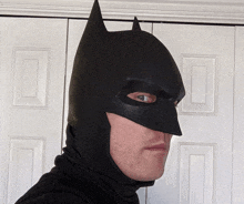 a man wearing a black batman mask looks to his left