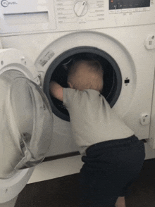 a baby is looking into a clavel washing machine