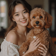 a woman is holding a small brown dog with a necklace that says j.s. on it