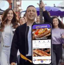 a man holding a guitar and a phone that says getiryemek on it