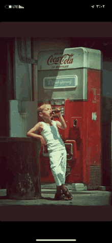 a young boy drinks from a coca cola machine