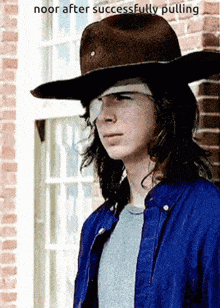 a young man wearing a cowboy hat with a bandage on his eye is standing in front of a brick building