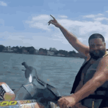 a man is riding a jet ski on a lake and making a peace sign .