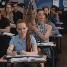 a girl with red hair is sitting at a desk in a classroom with other students and the word schitts creek on the bottom