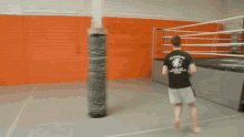 a man in a black shirt is standing in a gym near a boxing ring and a sign that says hk