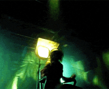 a person is sitting in a chair in a dark room with a yellow light in the background .