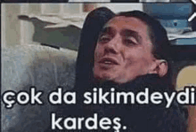 a man is laying on a couch with his arms crossed and a caption that says `` çok da sıkımdaydi kardes ''