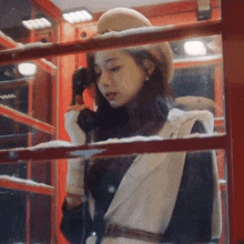 a woman in a hat is talking on a phone in a red telephone booth .