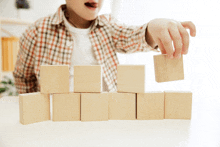 a child is playing with wooden blocks on a white table