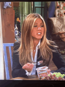 a woman sits at a table with a cup of ben & jerry ice cream in front of her