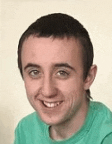 a young man is wearing a green shirt and smiling for the camera .