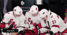 a group of hockey players are looking at a tablet with the number 37 on the back of their jersey