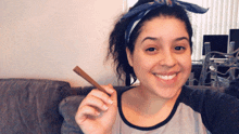 a woman wearing a headband is smiling while holding a cigarette