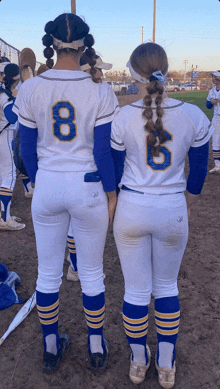 two softball players standing next to each other with one wearing the number 8