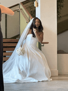 a woman in a wedding dress is standing in front of stairs