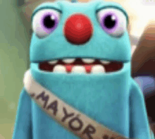 a blue cartoon character with a red nose and a mayor 's sash around his neck