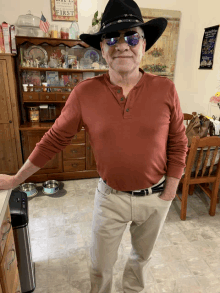 a man wearing a cowboy hat and sunglasses is standing in front of a sign that says first