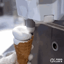 a person is holding an ice cream cone in front of a machine that is making ice cream .