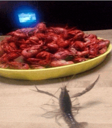 a plate of crawfish sits on a wooden table next to a shrimp