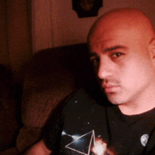 a bald man wearing a black t-shirt with a triangle on it