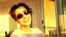 a young boy wearing sunglasses and a white shirt is smiling .