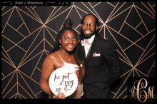 a man and woman pose for a photo with a sign that says " he put a ring on it "