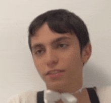 a man wearing a bow tie and suspenders is looking at the camera