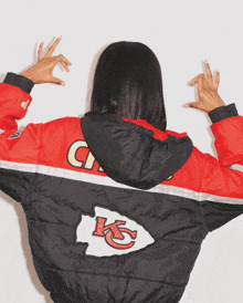 a woman wearing a red black and white jacket with the letters kc on the back