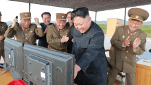 a group of men in military uniforms are standing around a television