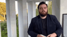 a man with a beard is standing in front of a white railing .