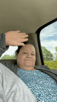 a woman in a car with her hand on her forehead