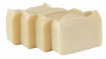 three pieces of white soap are stacked on top of each other on a white surface .