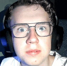 a man wearing glasses and headphones looks surprised