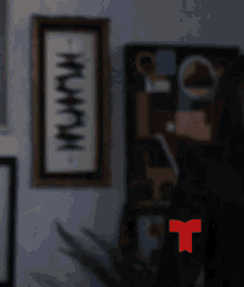 a woman is standing in front of a wall with a framed picture on it that says ' muwahn '