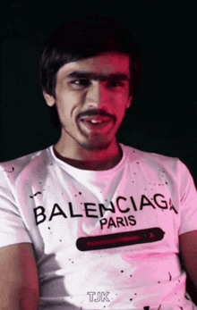 a man wearing a balenciaga paris t-shirt is smiling