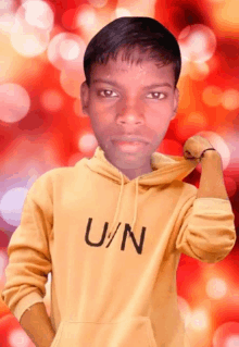 a young man wearing a yellow u/n hoodie flexes his arm