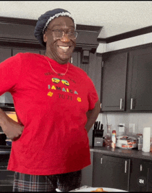 a woman in a red jamaica t-shirt smiles in a kitchen