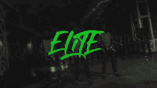 a group of people standing in a dark room with the word elite written in green