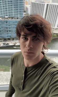 a man in a green shirt stands on a balcony overlooking a city