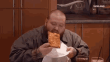 a man with a beard is eating a large slice of pizza .