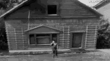 a black and white photo of a man standing in front of a house with the word vallam on the bottom