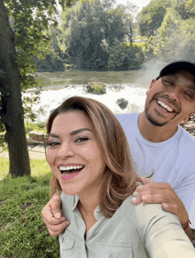 a man and a woman are posing for a picture and smiling in front of a waterfall