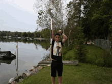 a man holding a pole in front of a lake with a boat in the background that says jet ski