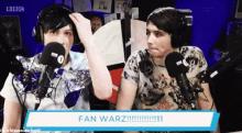 two men are sitting in front of microphones and a sign that says fan warz !!!